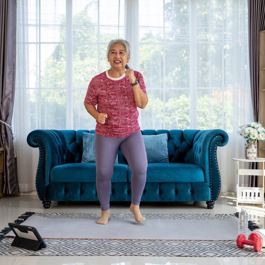 Active woman in her 60s training with dumbbells in her home