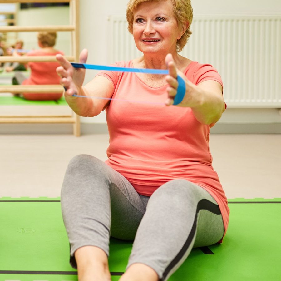 Woman in her 60s smiling and exercising at home, relaxed and comfortable