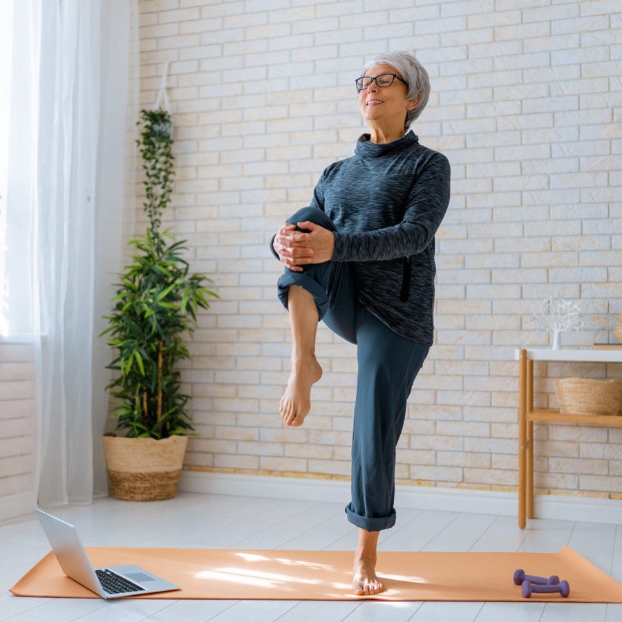 Woman with short grey hair exercising with balance and strength in a calm home setting