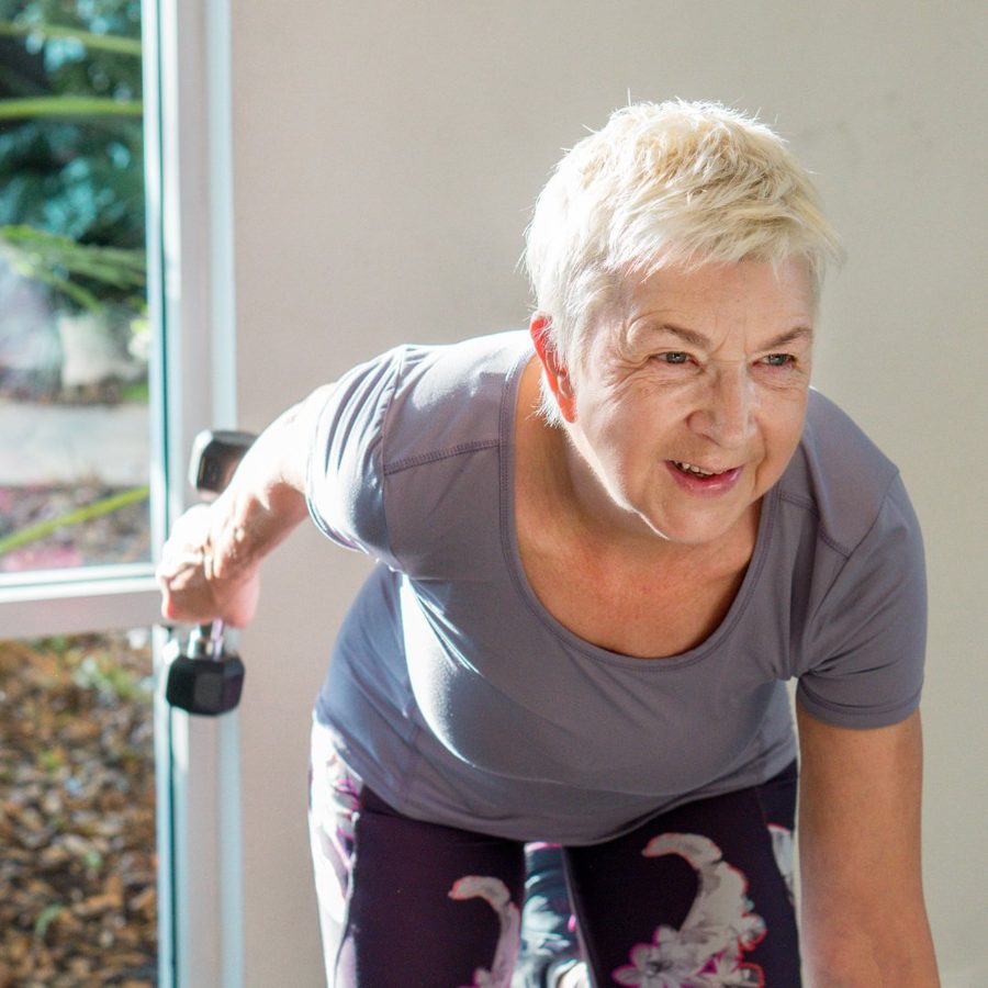 Woman in her 60s carrying grocery bags from her car to her home, confident and capable